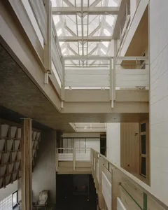 A modern building with a wooden staircase surrounded by glass walls and a glass ceiling, allowing natural light to enter and creating a bright and open atmosphere