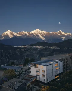 寧靜山間住宅，擁有現代外觀、黑色屋頂與大片窗戶，周圍環繞如畫景觀，背景有壯麗山脈