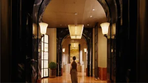 A woman walks through a grand hallway with marble flooring and a high ceiling, creating an elegant and sophisticated atmosphere
