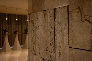 A dimly lit room with a modern stone wall, contrasting with a white floor, creating a moody atmosphere