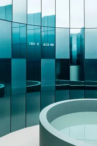 A modern room with a circular mirror on the wall, surrounded by a circular frame, in a blue color scheme, with a clean and minimalistic atmosphere