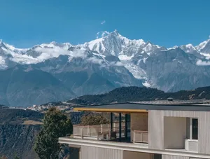 一座現代住宅配有木造露台，周圍環繞森林，背景有山巒，自然陽光營造溫暖氛圍