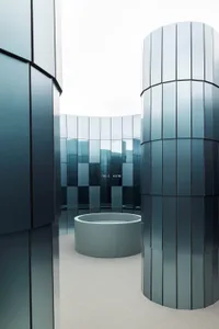 A modern building with a large, open space featuring a circular pool and large windows allowing natural light to fill the space