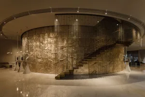A grand marble staircase with a metal railing in a well-lit hallway, captured from a low angle to emphasize its height and grandeur