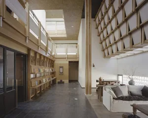 A modern, open-plan living space with wood and concrete features, filled with furniture and natural light from the windows