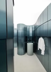 A modern bathroom with a blue color scheme, featuring a sink, towel rack, and shower, with a clean and well-maintained atmosphere
