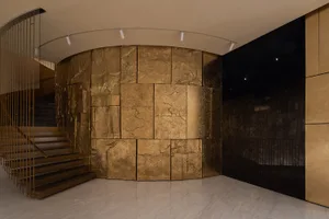 Luxurious living space with a gold-colored accent wall, a staircase, and natural light from windows