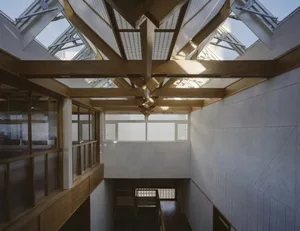 A large, open room with a wooden floor, skylight, and natural light, featuring a staircase and seating areas