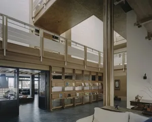 A well-lit room with wooden floors and walls, filled with organized bookshelves and various books, creating a calm and inviting atmosphere for learning and knowledge