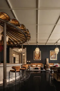 Cozy living room with a bar area, featuring a mix of wood and metal furniture, potted plants, and dim lighting