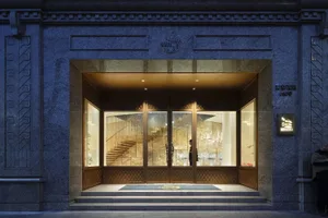 A grand entrance with a large doorway featuring a golden design and a wooden staircase, set in a sophisticated architectural space