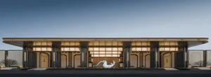 一座現代建築，側邊有一座大型人物金屬雕塑，背景明亮晴朗