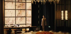 A woman stands near a dining table with chairs and tableware in an elegant and inviting restaurant-style dining space