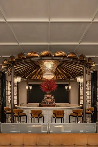 A modern bar with a circular design, surrounded by chairs and a vase with flowers, set in a well-lit space with a warm atmosphere