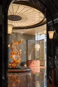 A modern lobby with a glass sculpture on a marble surface, surrounded by a pink and brown color scheme, and natural light from a large window