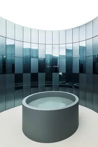 A modern room with a circular pool surrounded by glass walls, creating an open and airy atmosphere