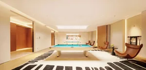 A modern game room with a pool table, leather chairs, and a couch, surrounded by wood accents and well-lit for a relaxed atmosphere