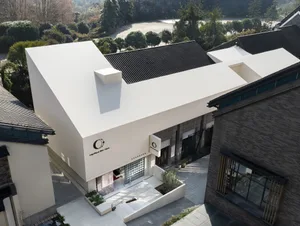 一棟擁有白色屋頂和大型白色牆面、搭配圓形窗戶的現代建築，置於明亮且光線充足的背景中