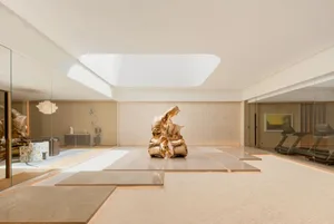 A modern lobby with a large golden sculpture, surrounded by potted plants and natural light from a large window