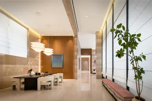 A well-lit modern dining room with a large window, wood furniture, and glass accents, featuring artwork on the walls and a comfortable atmosphere