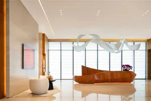 Bright and welcoming lobby with a white marble floor, natural light, and a modern sculpture hanging from the ceiling