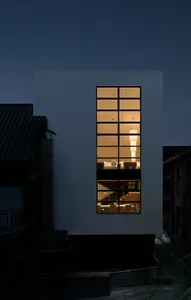 A large white house with a modern design, featuring a large glass window and a bright, inviting interior with clean lines and minimalistic aesthetics