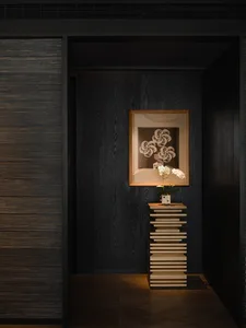 Cozy study with wooden floor, bookshelf, and door, featuring a vase with flowers and dim lighting