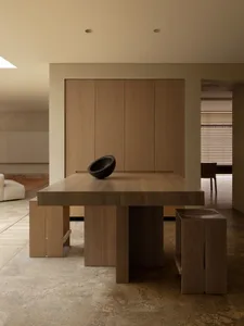 Warm and inviting kitchen with wooden floors, cabinets, and a dining table, featuring a cozy atmosphere with a potted plant and a chair