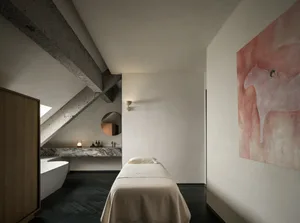 A cozy bedroom with a large bed, a mirror above, and a painting on the wall, creating a warm and inviting atmosphere