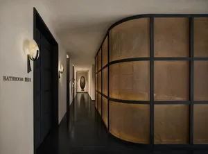 A dimly lit hallway with a black and white color scheme, lined with large brown wooden panels creating a modern and sophisticated atmosphere
