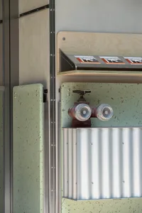 A dimly lit industrial room with a red and white fire hydrant mounted on a metal wall, set against a concrete floor