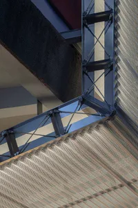 A modern metal staircase with a black railing in a public space with urban architecture
