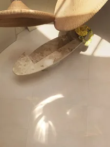 A modern bathroom with a white bathtub on a tiled floor, a hat hanging on the side of the tub, and a clean and organized atmosphere