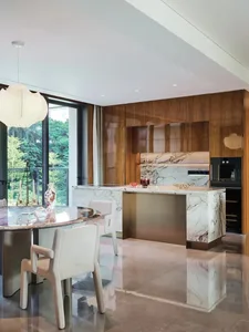 Modern kitchen and dining area with a large island, marble countertop, and comfortable seating arrangement, decorated with a vase and potted plant