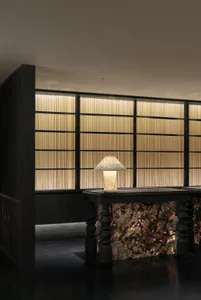 Well-lit hotel lobby with a black marble counter and a metal lamp, set against a modern backdrop