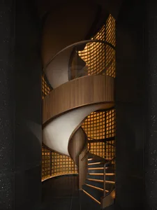 A spiral staircase in a dark room with a wooden staircase and metal railing