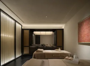 Cozy hotel room with a brown color scheme, featuring a large bed, counter, and sink, with toiletries and amenities scattered around