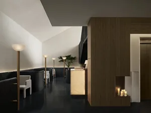 Dimly lit bathroom with a wooden door, marble counter, and sink, creating a warm and inviting ambiance