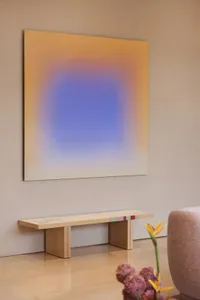 溫馨的客廳空間，牆上掛著現代藝術畫作，配有木製長椅和椅子，採用黃藍配色