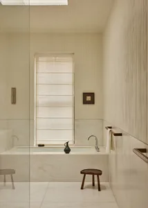 Modern bathroom with a white bathtub, natural light from a large window, and a clean, minimalistic design