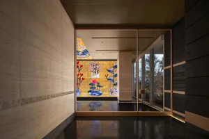 A modern room with a black and white tile floor, a large window, a door, and a wall with a colorful painting of flowers in a dimly lit space
