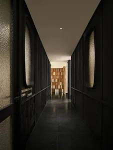 A dimly lit hallway with a black and white color scheme, lined with doors and made of wood