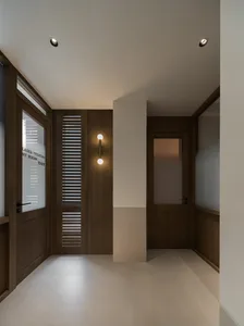 A well-lit hallway with a wooden floor and white walls, featuring an open doorway and a window on the left side