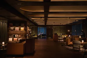 A living room or lobby with a car parked inside, featuring a wooden floor and a large window, with an elegant and inviting atmosphere