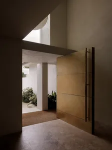 Warm and inviting room with a gold door, white interior, and plants, creating a sense of elegance and comfort