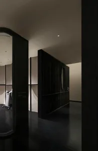 黑白攝影，呈現酒店走廊、黑色門扇、木質地板，以及用作行李收納的行李箱