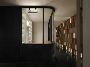 A dimly lit bathroom with a modern design, featuring a large mirror and a sink, made of wood