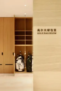 一間帶有木質門板與地板的球具收納室，牆上整齊排列著多個不同尺寸的球具袋，陽光從門口自然灑入
