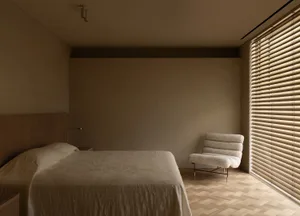 A calm and inviting bedroom with a bed, chair, and window, featuring a mix of modern and traditional styles, neutral colors, and wooden elements, with natural light streaming in through the window