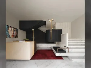 Modern living space with a spiral metal staircase, a red rug, and a white marble wall, featuring a mounted TV and clean lines